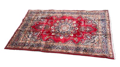 Lot 392 - A red ground hand knotted woollen carpet, with...