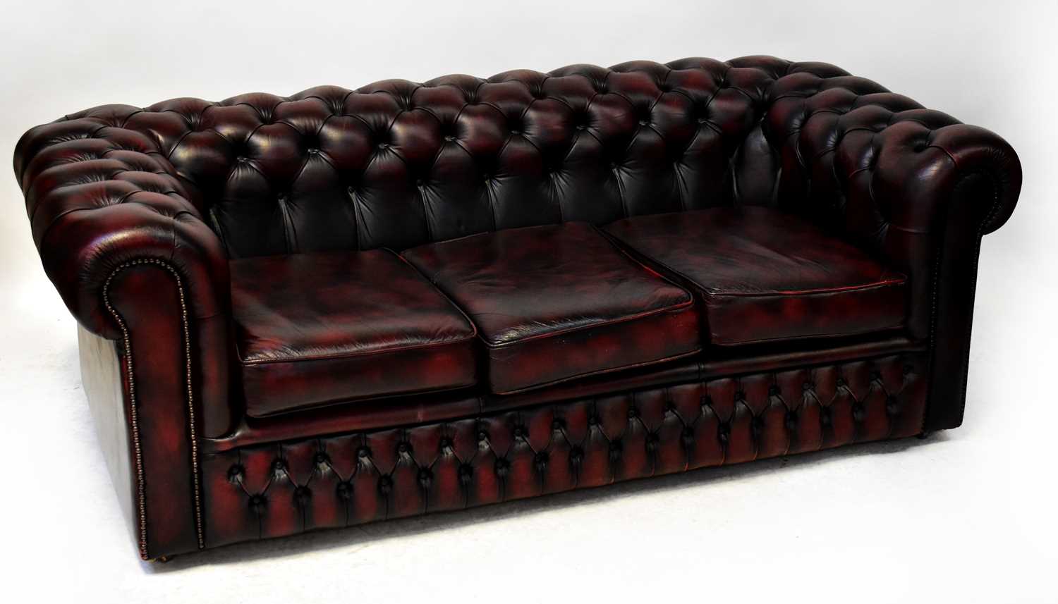 Lot 70 - CHESTERFIELD; an oxblood leather three-seat...