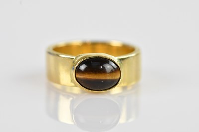 Lot 2347 - A yellow metal tiger's eye set cabochon ring,...