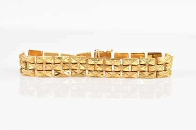 Lot 1100 - A yellow metal textured three bar bracelet,...