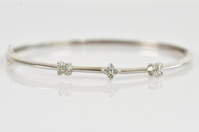 Lot 1201 - A 9ct white gold hinged snap bangle, set with...