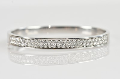 Lot 1110 - An 18ct white gold diamond set hinged bangle,...