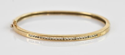 Lot 1178 - A 9ct yellow gold channel set diamond hinged...
