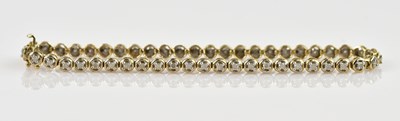 Lot 1203 - A 9ct yellow gold diamond set tennis bracelet,...