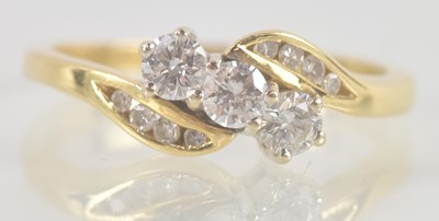 Lot 1303 - An 18ct yellow gold diamond crossover set ring,...