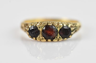 Lot 2563 - A yellow metal garnet set three stone dress...