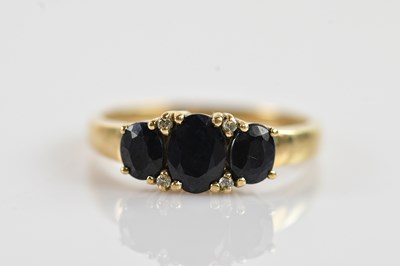 Lot 660 - A yellow metal and sapphire three stone ring,...