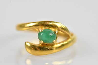 Lot 2438 - A yellow metal emerald set crossover ring,...