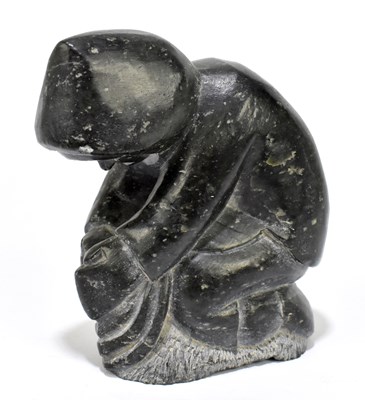 Lot 1033 - An Inuit carved green stone figure of an Eskimo kneeling