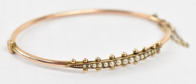 Lot 912 - A 9ct yellow gold bangle set with fifteen seed...