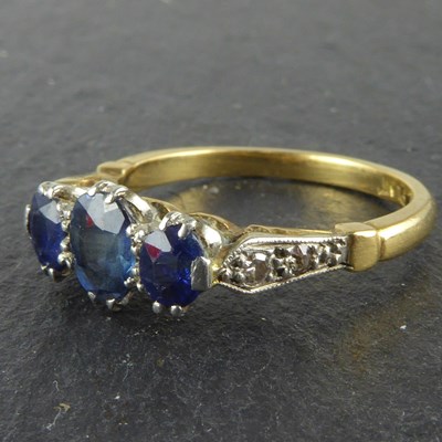 Lot 1041 - An 18ct gold three stone sapphire ring with...