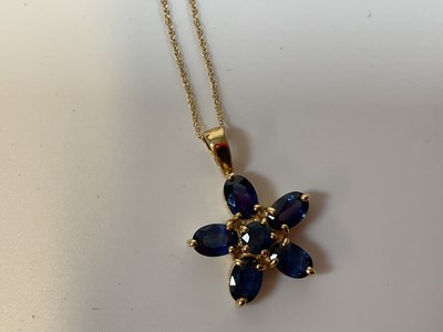 Lot 329 - A 9ct gold flower shaped pendant set with blue...