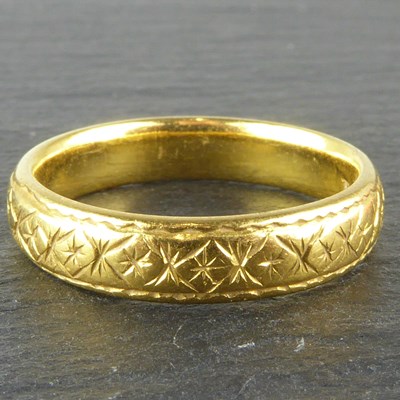 Lot 1017 - A 22ct gold band ring with textured pattern,...