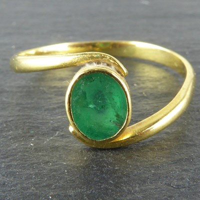 Lot 1087 - An 18ct gold ring with bezel set oval green...