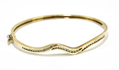 Lot 1180 - A 9ct gold snap bangle set with clear stones,...