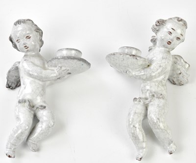 Lot 231 - A pair of tin glazed cherub wall sconces,...