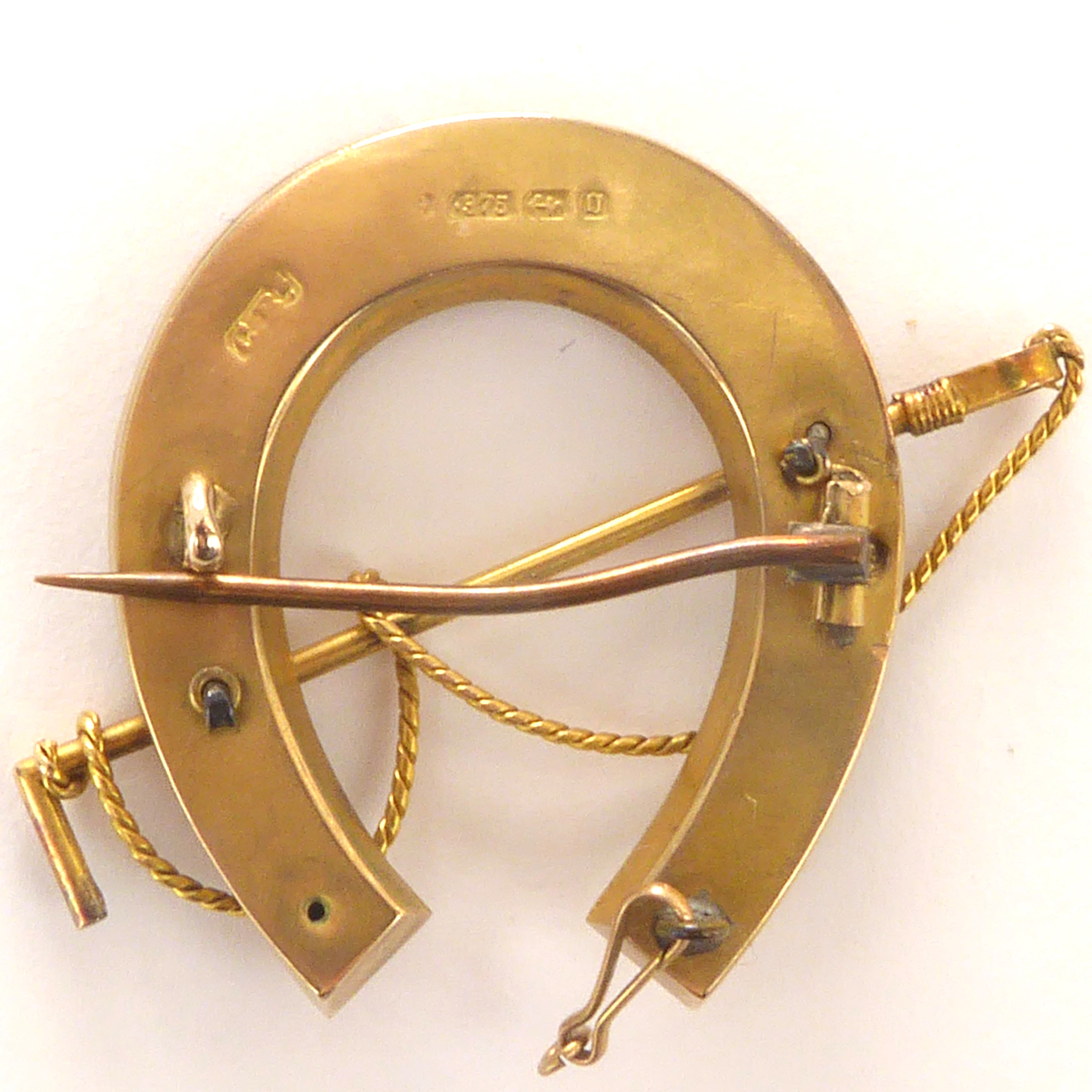 Lot 1064 - A 9ct gold horseshoe and riding crop brooch,