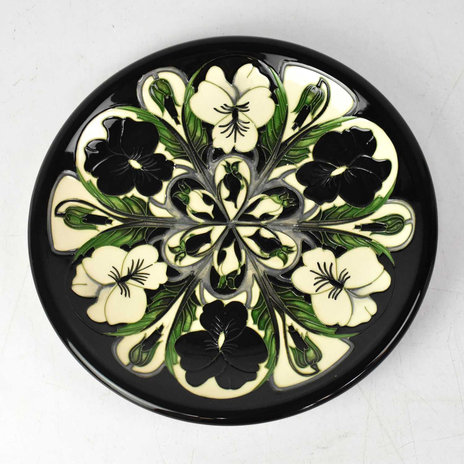 Lot 247 - MOORCROFT; a pansy pattern plate with black...