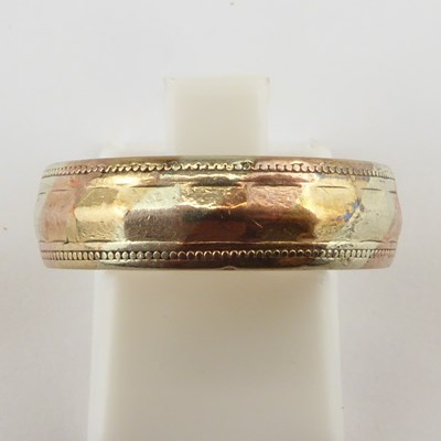 Lot 909 - A 9ct gold wedding band with facet decoration...