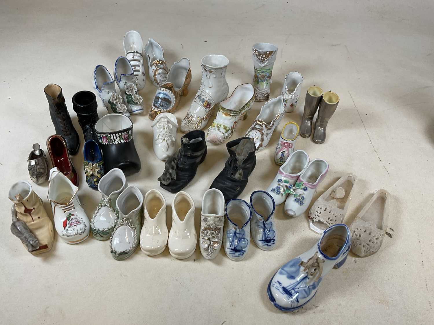 Lot 188 - A collection of ornamental ceramic shoes, many...