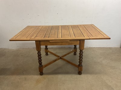 Lot 621 - A light oak draw-leaf table raised on barley...