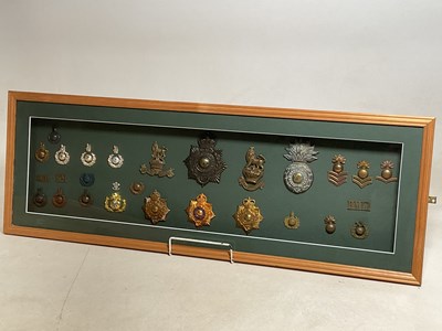 Lot 115 - A framed and glazed display of cap badges and...