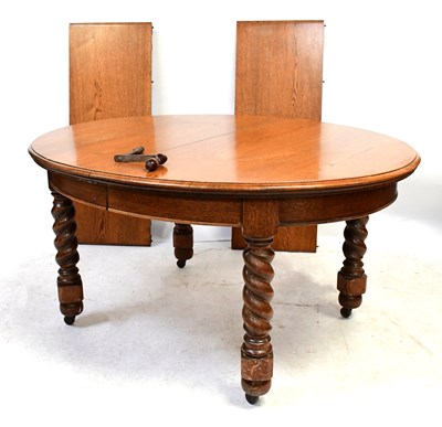 Lot 50 - A circular oak dining table with two extra...