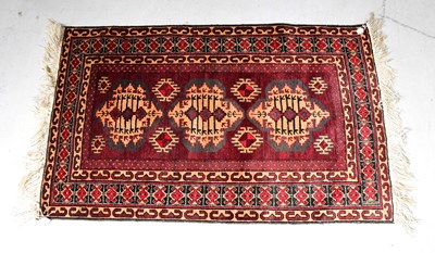 Lot 128 - A small red ground hand knotted rug with three...