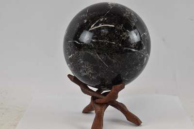 Lot 213 - A fossiled stone orb on folding wooden base,...