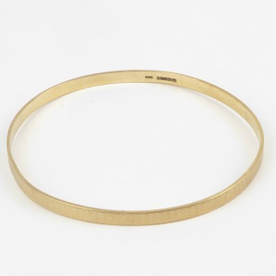 Lot 1024 - A 9ct gold bangle with engine turned...