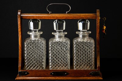 Lot 3 - An early 20th century oak tantalus with silver...
