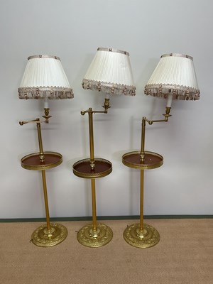 Lot 328 - A set of three 20th century brass floor lamps...