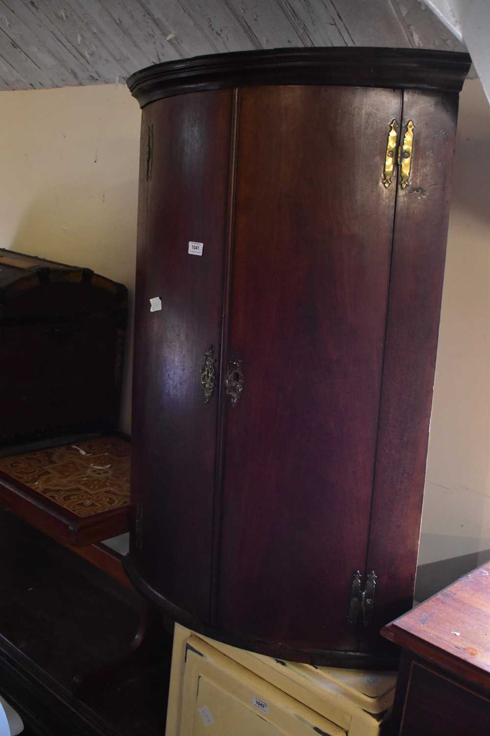 Lot 1041 - A Georgian mahogany bowfront corner cupboard.