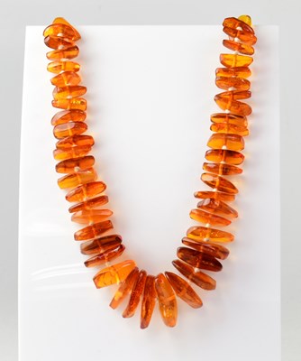 Lot 1110 - An amber-style bead necklace of naturalistic...