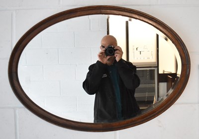 Lot 99 - A 1920's oak framed oval overmantel mirror,...