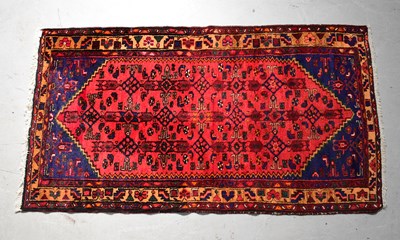 Lot 94 - A hand knotted red ground rug with geometric...