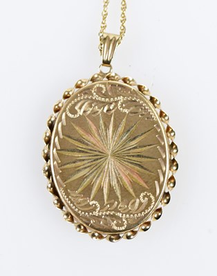 Lot 432 - A 9ct yellow gold engraved oval locket...