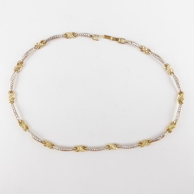 Lot 1106 - A 14K semi-rigid necklace with knot and white...