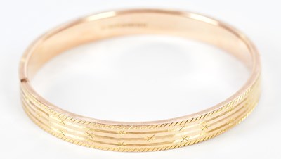 Lot 541 - A 9ct rose gold bangle with engraved detail,...