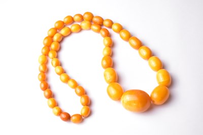 Lot 426 - A strand of egg yolk amber coloured beads,...