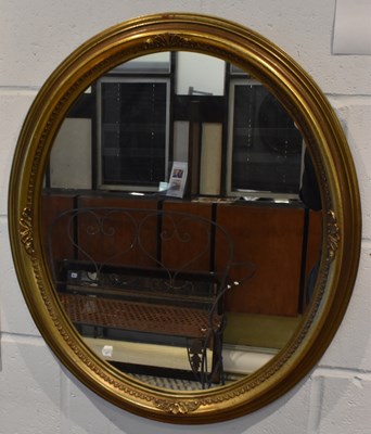 Lot 99 - A reproduction oval gilt framed wall mirror,...