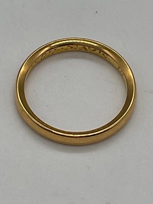 Lot 409 - A yellow metal wedding band with inscription...