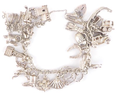 Lot 1076 - A hallmarked silver charm bracelet with twenty-...