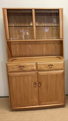 Lot 587 - ERCOL; an elm glazed cabinet with cupboards to...