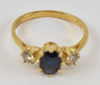 Lot 807 - An 18ct yellow gold ring set with central blue...