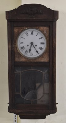 Lot 173 - A 1920s oak wall clock, the white painted dial...