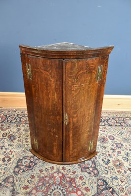 Lot 168 - A Georgian oak bowfronted corner cupboard,...