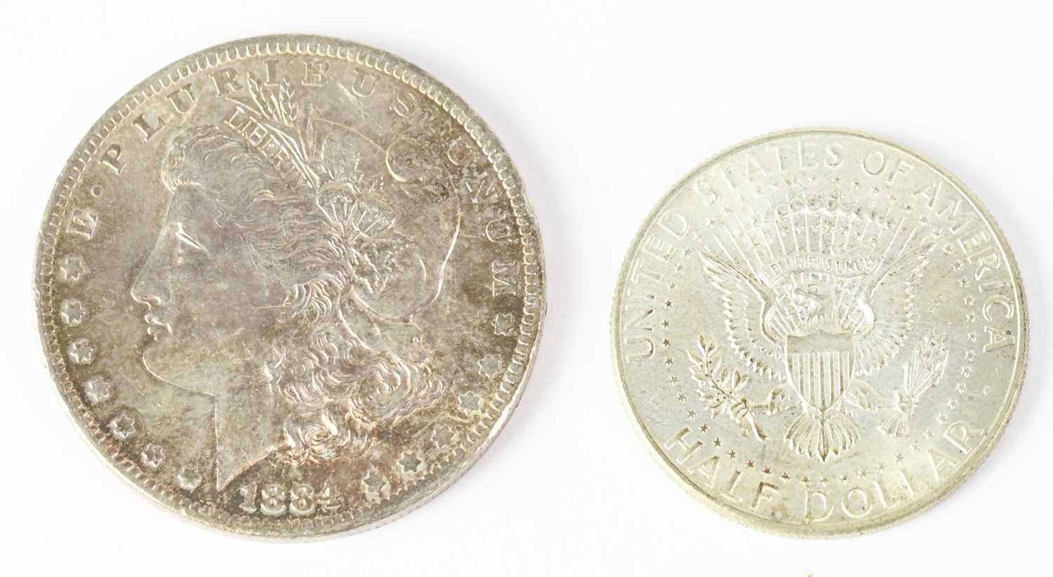 Lot 692 - An 1884 US silver dollar and a US 1964 half...