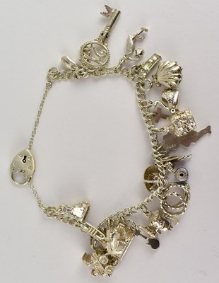 Lot 815 - A silver charm bracelet with twenty charms to...