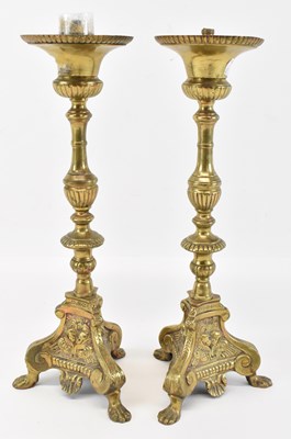 Lot 457 - A pair of brass candlesticks, with cherub...